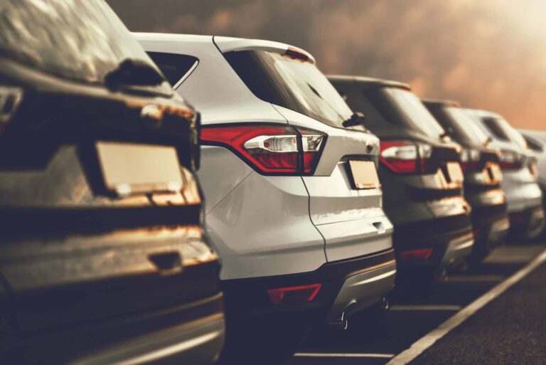 A view of the back of several cars lined up in a car park.