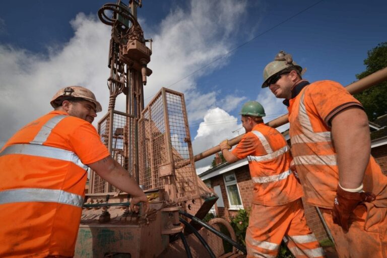 Three workmen using a borehole drill rig for ground source heat pumps.