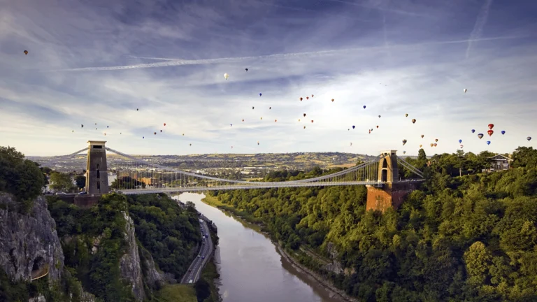 Clifton suspension bridge with hot air balloons in background.