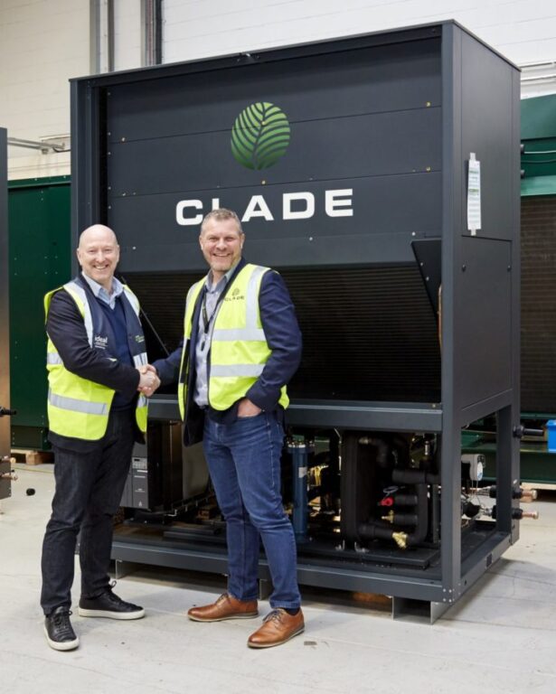 Two men are shaking hands in front of a refrigerant heat pump, sealing a deal that secures a major investment for Clade Engineering.