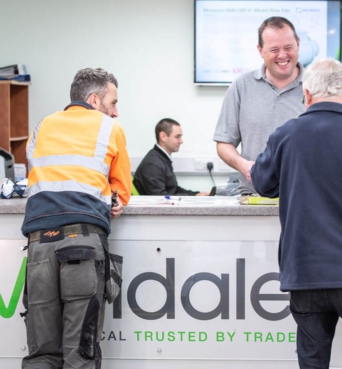 A man is happily serving a customer on the reception desk at Devondale Electrical Distributors.