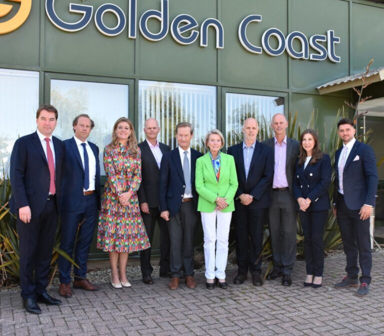 A group of people standing outside the office of Golden Coast.