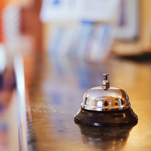 A gold hotel service bell sits on a counter top.