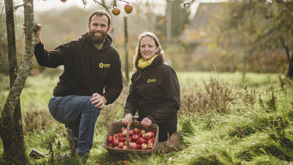 Owners displaying a basket of apples in orchard at Hunts Cider