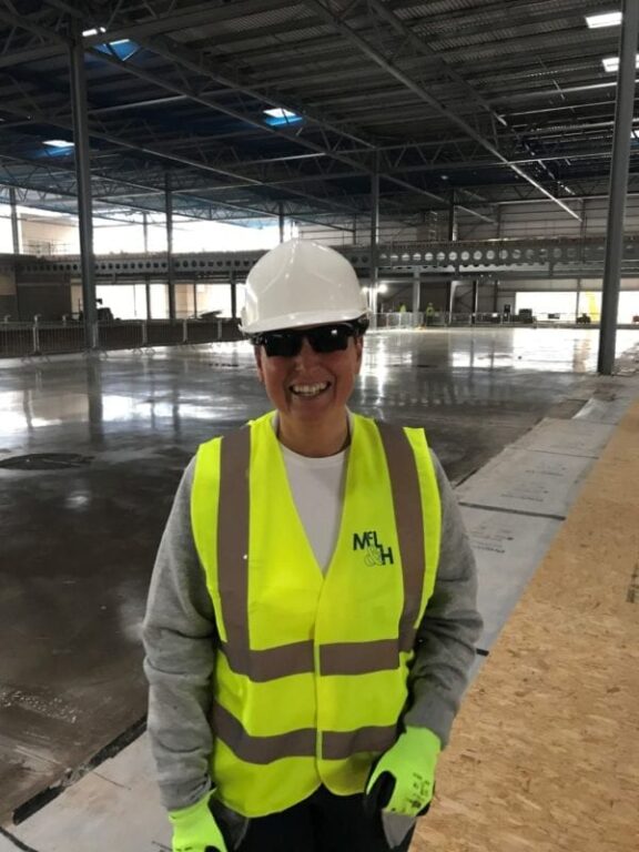 Maureen Gori de Murden is stood at a construction site, donned in safety equipment, beaming at the camera in honour of International Women's Day.