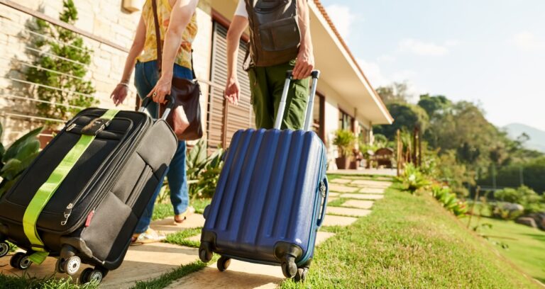 Two women pull their suitcases along a path leading to to their holiday accommodation.