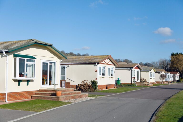 A row of bungalows lines the residential mobile home park, on a bright and sunny day.