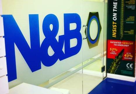 An N&B logo is depicted in blue on the walls of a room enclosed by glass.