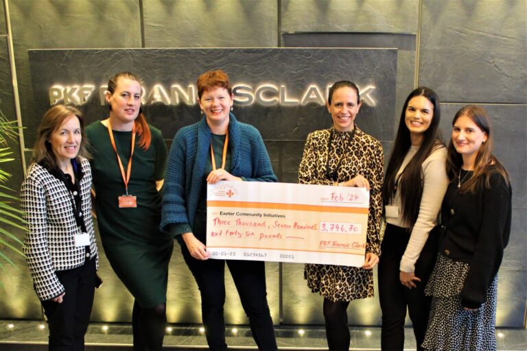 Several colleagues from the Exeter office stand holding a giant cheque, displaying the amount they have raised for Exeter Community Initiatives.