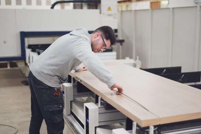 A man is in a workshop, sizing a door to the correct dimensions.