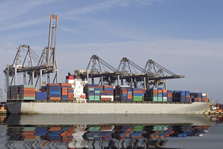 A container ship filled with cargo docked at Southampton port. the image reflected back by the water.