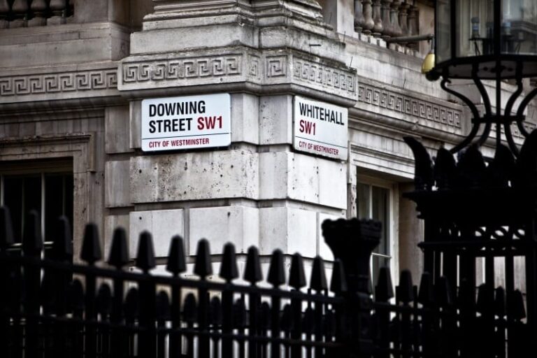 Two street signs on the corner of Downing Street and Whitehall Street in London.