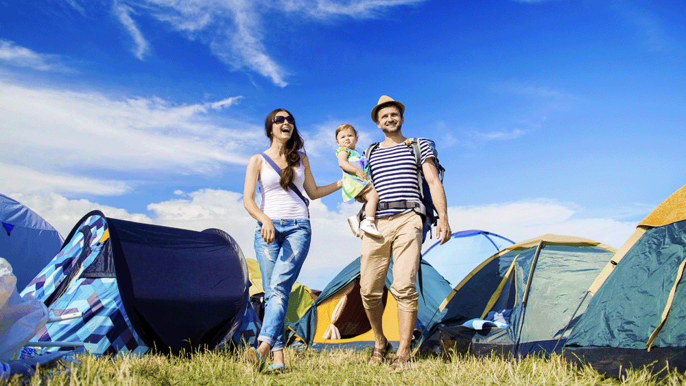 Family standing in field with camping tents.