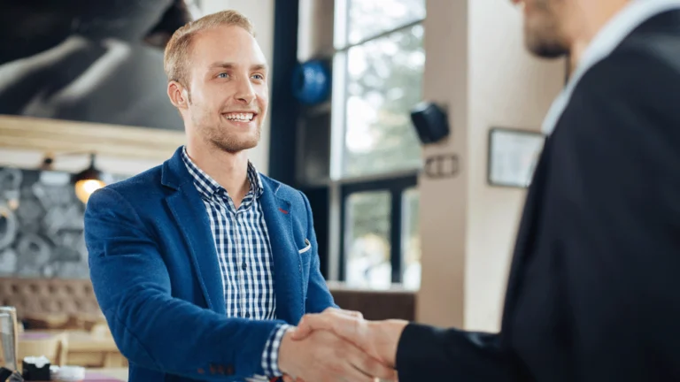 Two men are in a cafe shaking hands on a business deal.