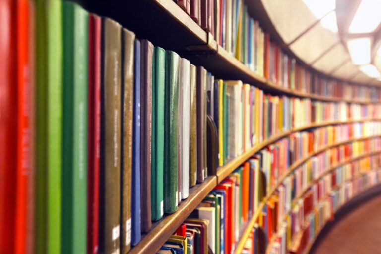 A large curving book shelf filled with stacks of colourful books.