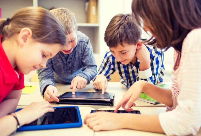 A group of primary school children work on computer tablets in the classroom.