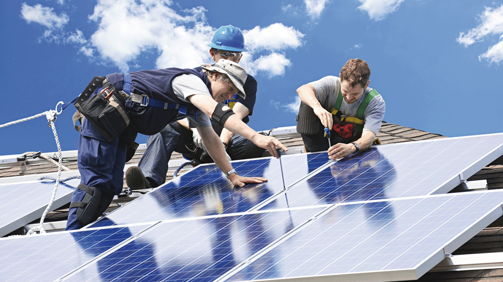 Three workmen attaching solar panels to a roof.