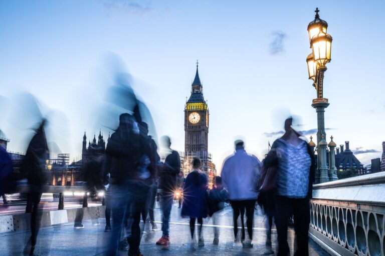 A blur of people at dusk crossing a London bridge heading towards Big Ben.