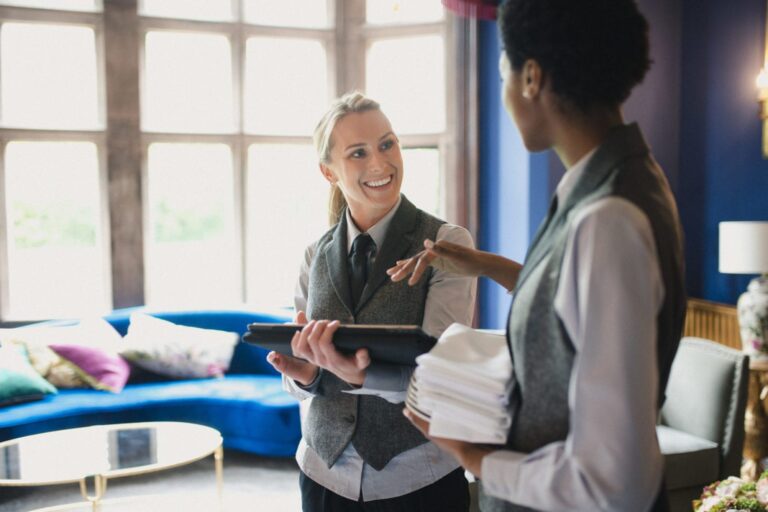 Two female hotel workers convers whilst carrying out their duties.