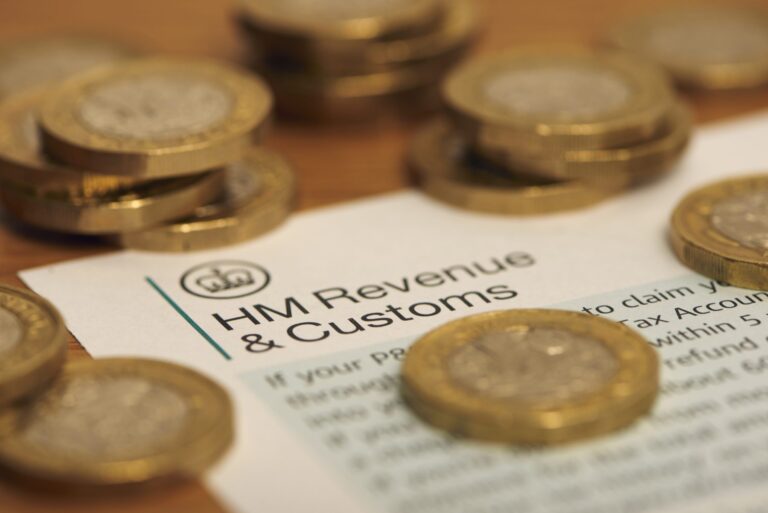 Several British pound coins are arranged in piles on top of an official document from HMRC.