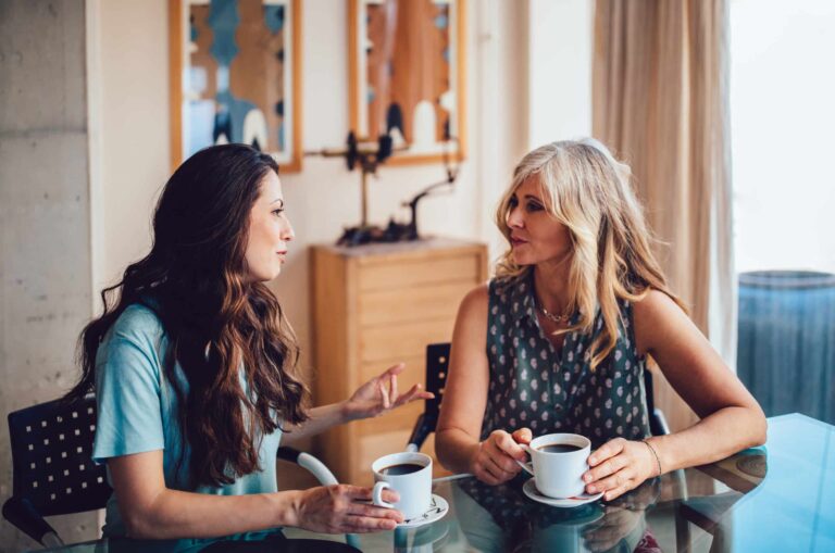 Two ladies are chatting over coffee.