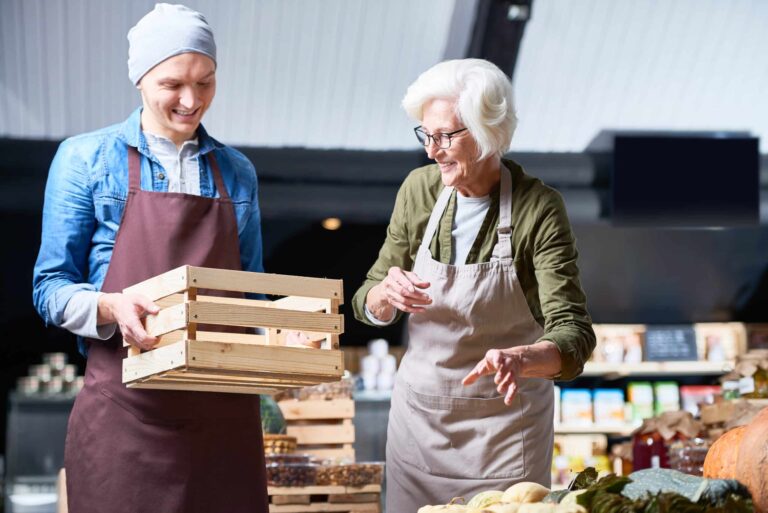 Two family members of different ages prepare to pack a crate with vegetables at their family-owned business.