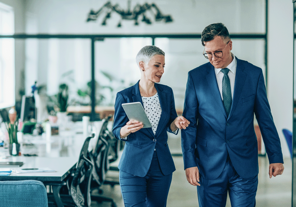 Two colleagues chatting whilst walking from a meeting room