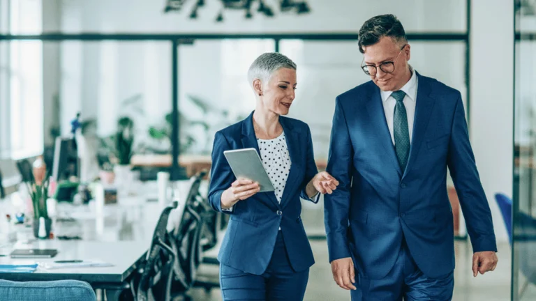 Two colleagues chatting whilst walking from a meeting room