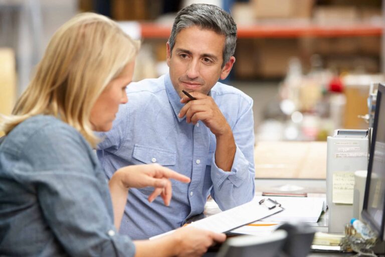 A client listens intently to his accountant as she gestures to information on a clipboard.