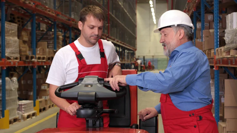 A man being taught how to use a piece of equipment in a warehouse