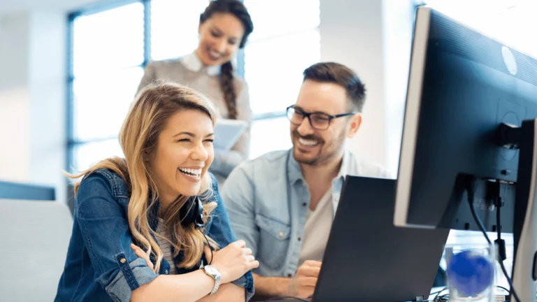 Colleagues laughing at something funny whilst looking at a computer screen