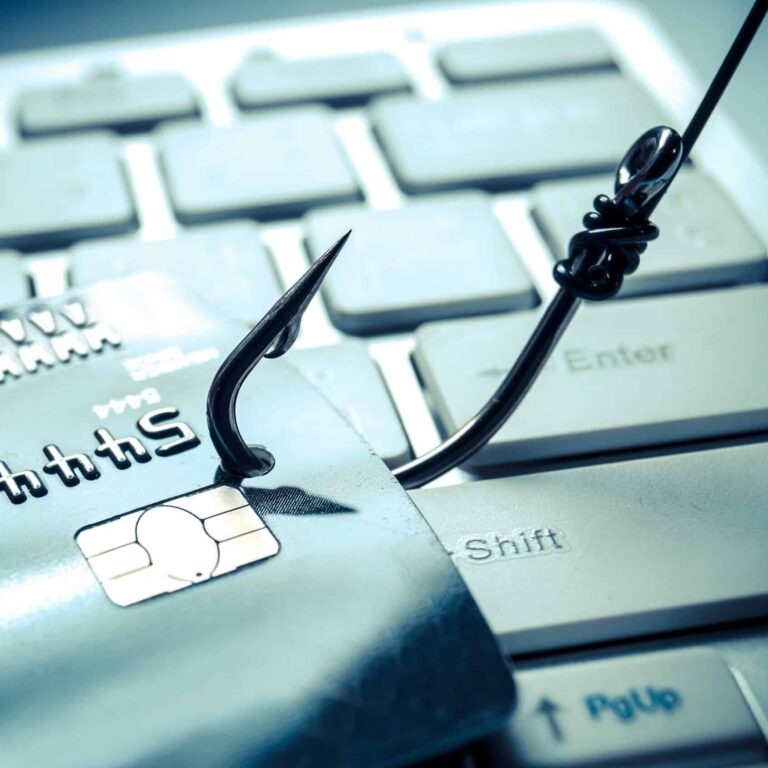 A close up of credit card being lifted off a keyboard by a fishing hook.