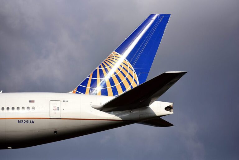 A United Airlines plane is flying through a very grey cloudy sky.