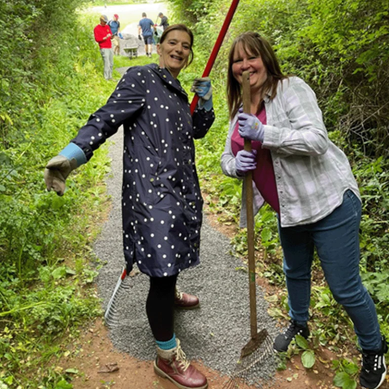 Torquay female colleagues on volunteering day with rakes on footpath