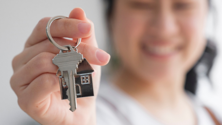 A young woman excitedly holding a house key.