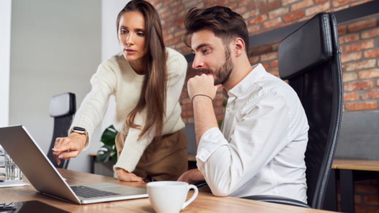 Two colleagues deep in thought discussing what they see on a laptop