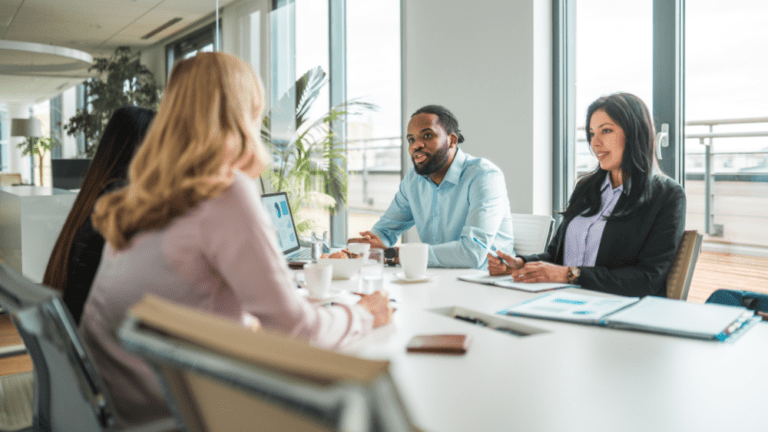 Employees of an international law firm sitting at a large table in a well-lit conference room.