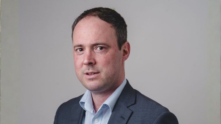 Nick Harris in a suit and open necked shirt