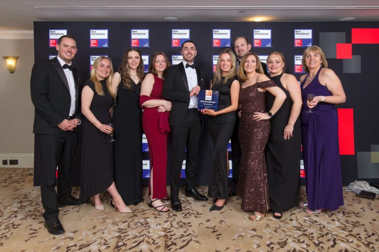 A group of 10 PKF Francis Clark colleagues posing with a trophy at the black tie Best Workplaces Awards event