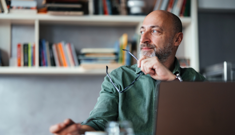 Man sitting at a laptop, looking out of the window