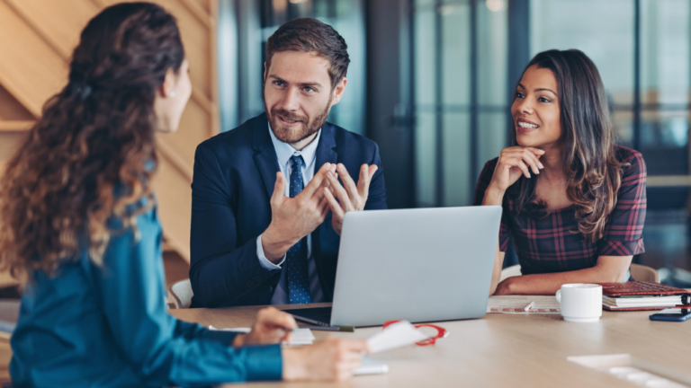 Group of business people in discussions sitting down around a laptop