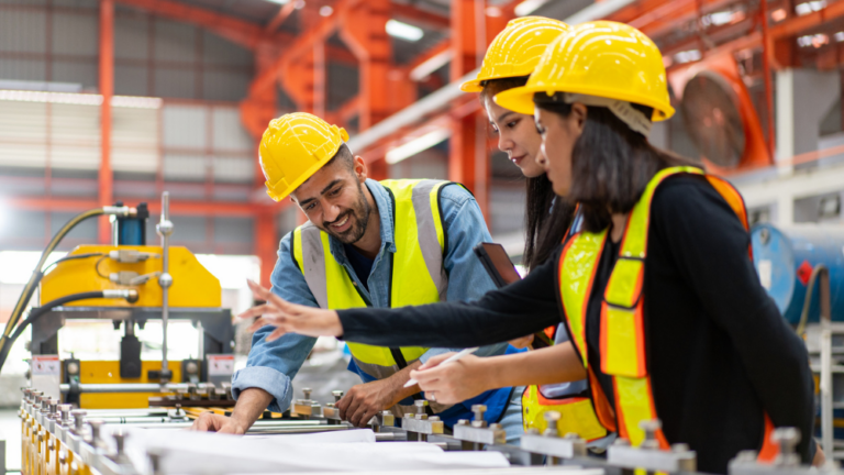 Three manufacturing workers looking at a piece of machinery